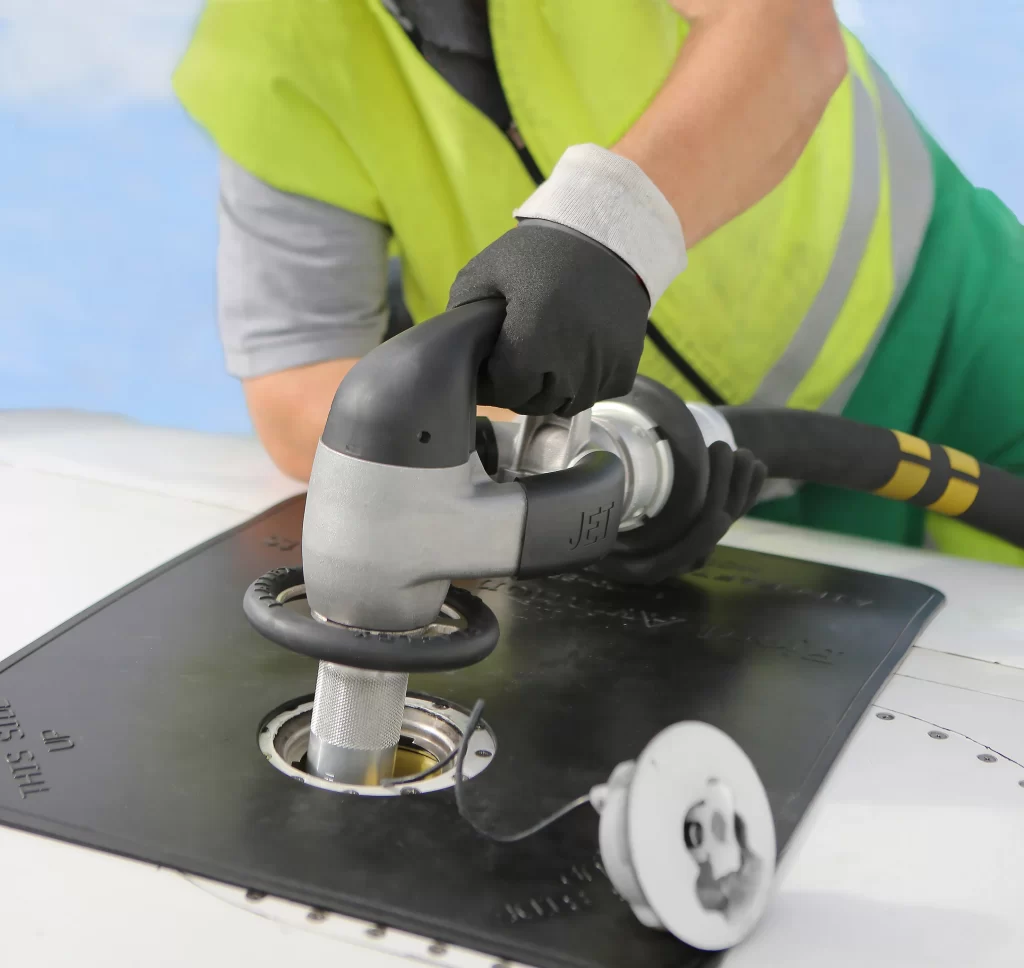 A overwing fuel nozzle being placed into an adapter onto of an aircraft wing. There is a removable rubber cover surrounding the cap.