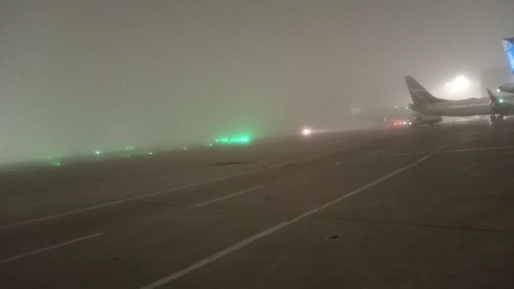 A picture of very heavy fog inside the airport. There is very limited  visibility, and it's impossible to see if a plane is hiding in the fog.